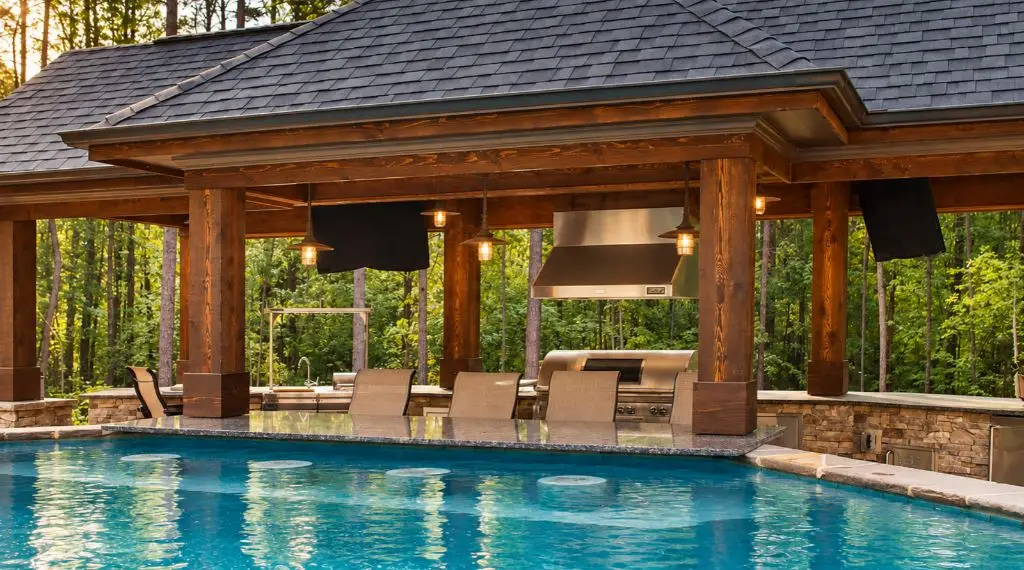 Backyard swimming pool with covered outdoor kitchen and island grill
