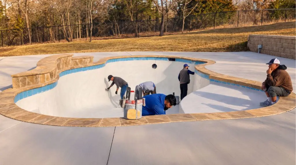 Gunite swimming pool construction with workers finishing the pool interior