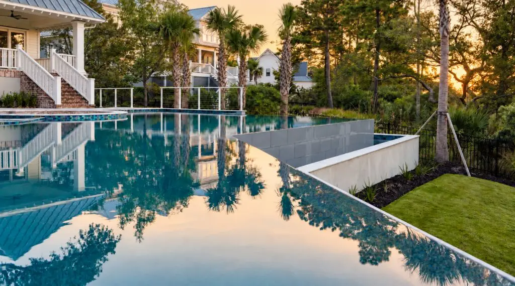 Infinity swimming pool with a vanishing edge overlooking a landscaped backyard