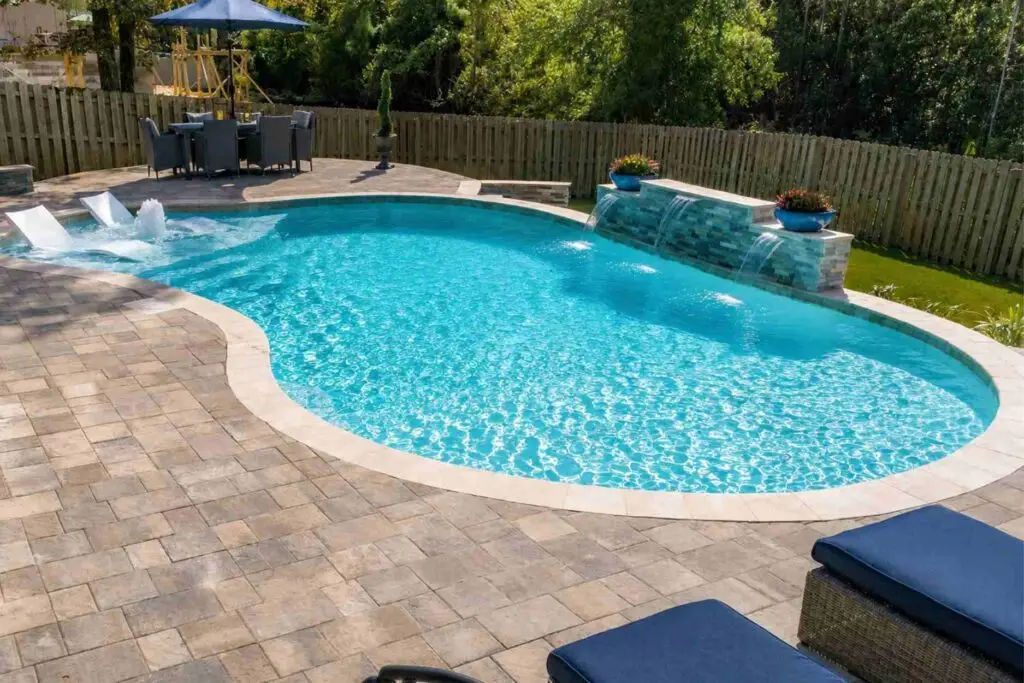 Kidney-shaped pool with three sheer descent waterfalls, a tanning ledge with in-water loungers and a wide paver deck