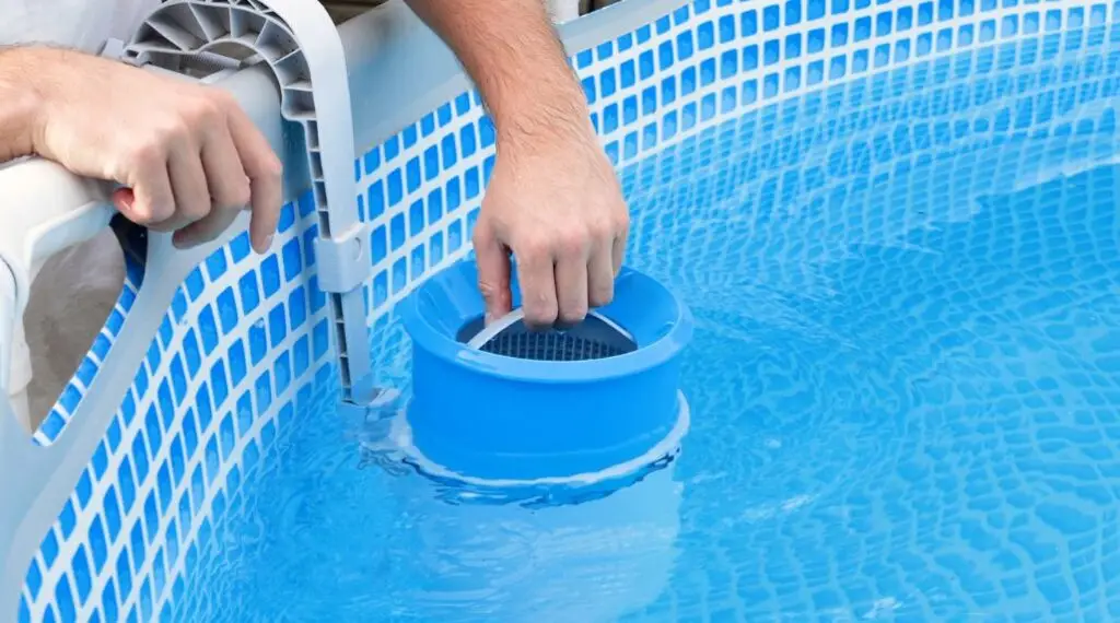 Person inspecting a swimming pool filter cartridge in clear blue pool water