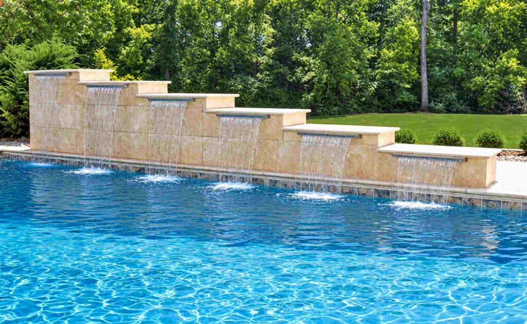 Staggered row of pool cascade waterfalls stepping down a raised limestone wall