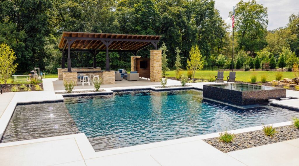 Custom swimming pool with a raised spa and outdoor pavilion, illustrating the importance of choosing a quality pool builder over the lowest price.
