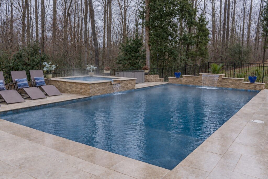 Steam rising from a heated spa beside an inground pool on an overcast winter day