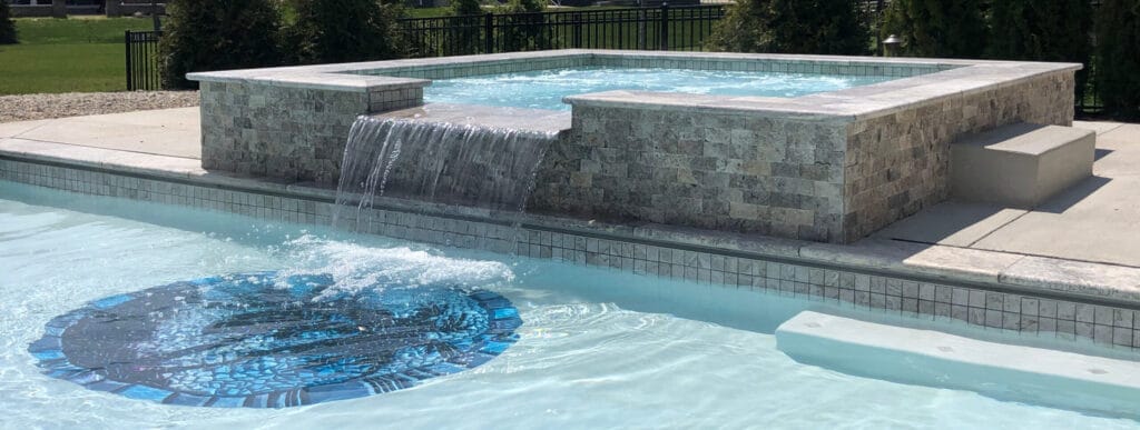 Custom spa on inground swimming pools with classical mosaic design in pool floor.