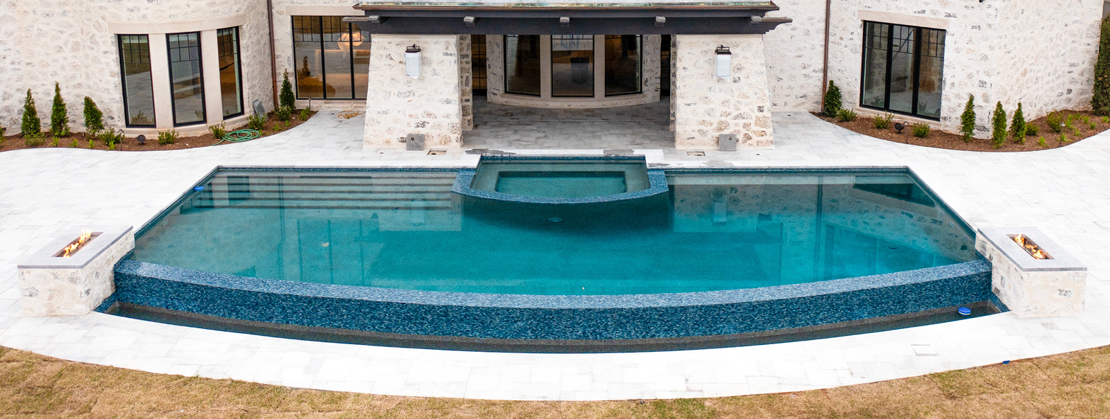 Ralegh pool with vanishing edge that is covered with glass tile.
