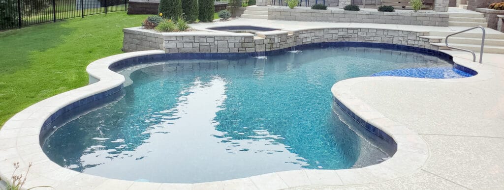 Curvy inground swimming pool with elevated spa.