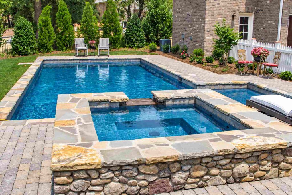 Flagstone pool coping on a rectangle pool and raised stacked stone spa with a paver deck