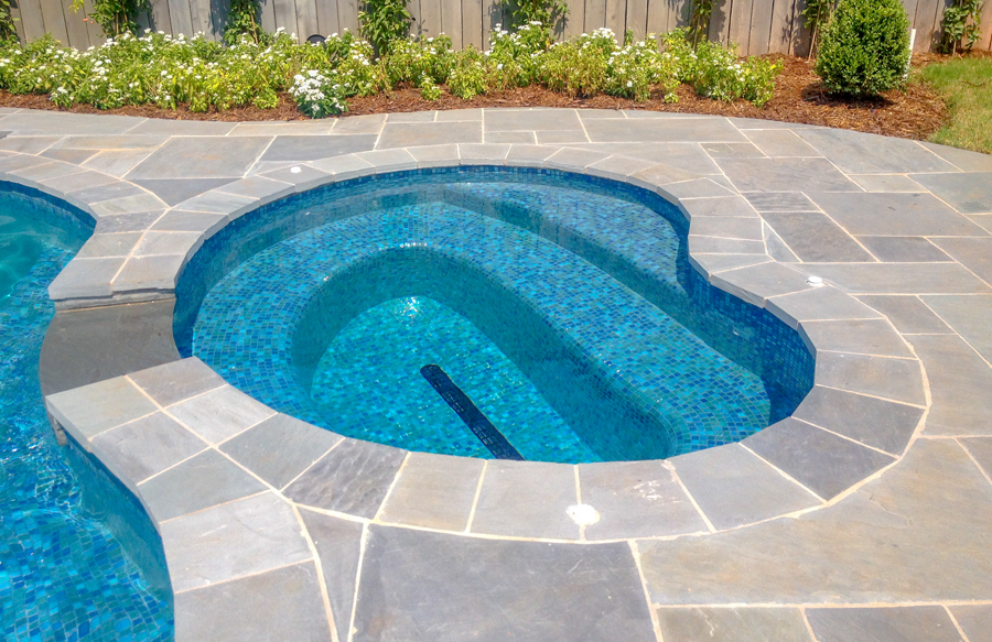 Free form glass tiled spa integrated with custom pool design