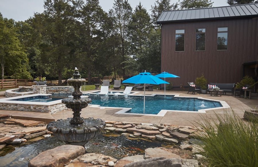 Custom backyard pool and raised spa beside a koi pond and fountain