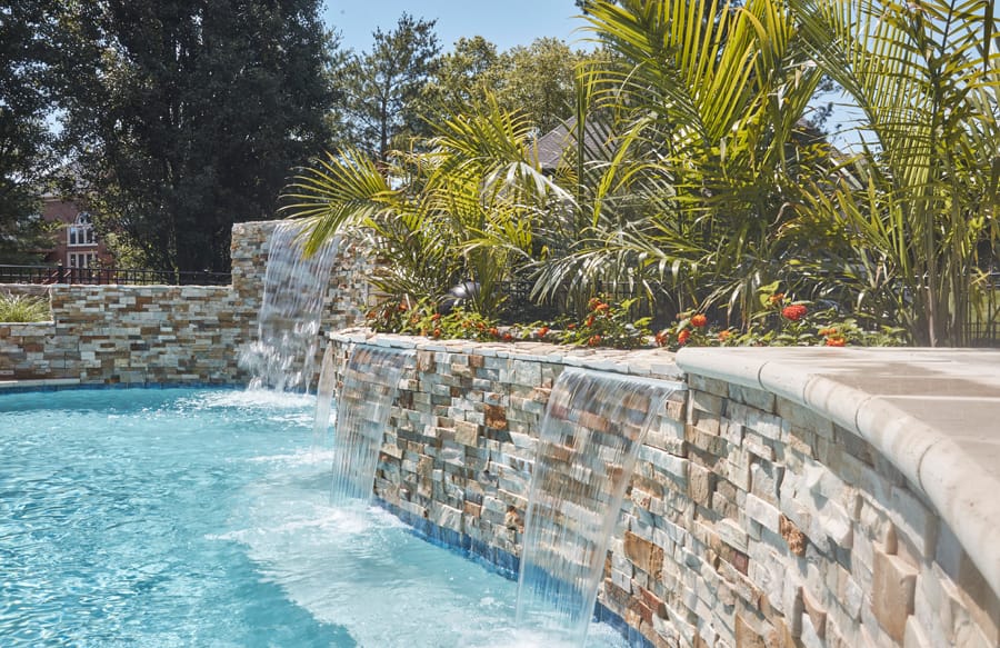 Natural stone waterfall flowing into a custom swimming pool