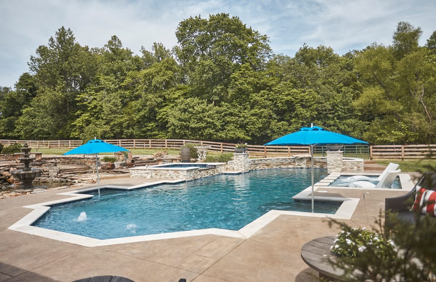 Custom geometric pool with raised spa, in-pool loungers and blue umbrellas
