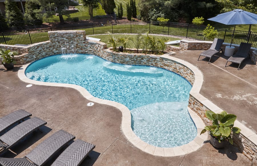 Freeform backyard swimming pool with bench and tanning ledge
