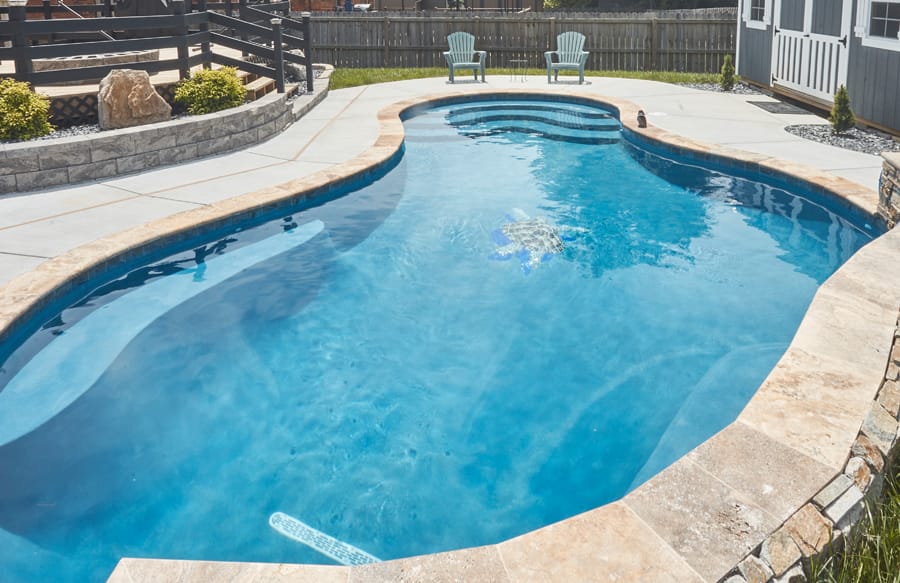 Freeform backyard swimming pool with natural stone coping