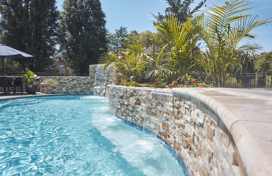 Freeform swimming pool with curved stone waterfall feature