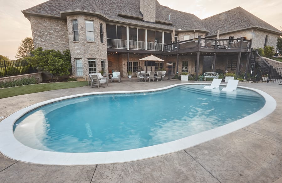 Freeform backyard pool with tanning ledge and seating area