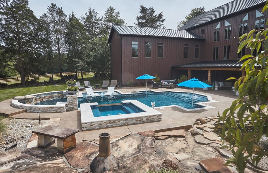 Luxury backyard pool with raised spa, lounging ledge and water features