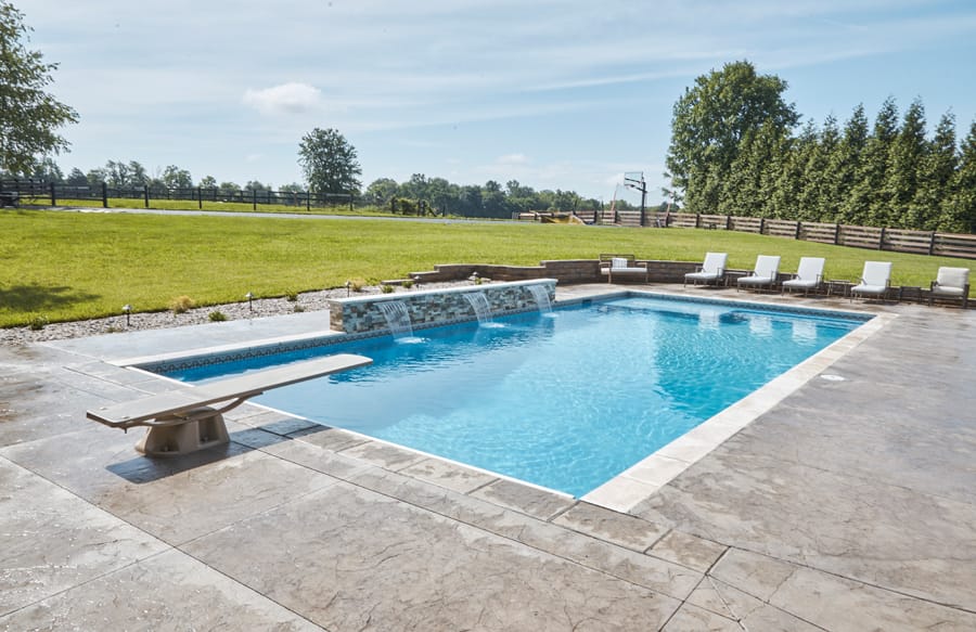 Luxury rectangular swimming pool with sun loungers and spacious patio