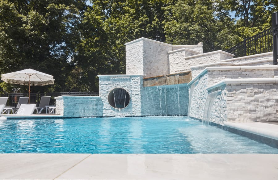 Custom pool with modern water feature wall and raised spa