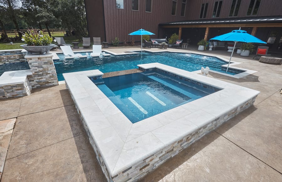 Raised square spa overlooking a custom geometric swimming pool