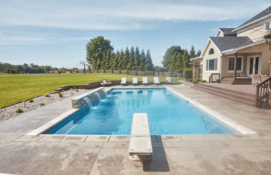 Rectangular swimming pool with diving board and modern backyard
