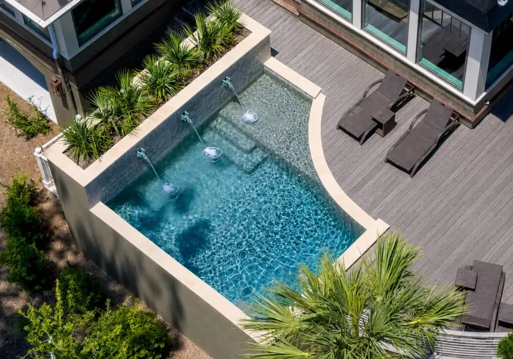 Aerial view of a compact rectangular pool beside a wood deck in a small backyard