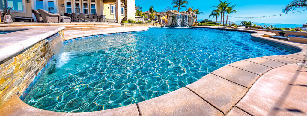 Curvy swimming pool with stack-stone wall with cascade water feature.
