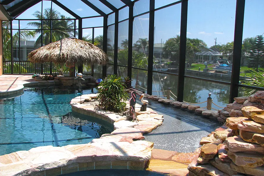 Lagoon style swimming pool with tropical backyard design