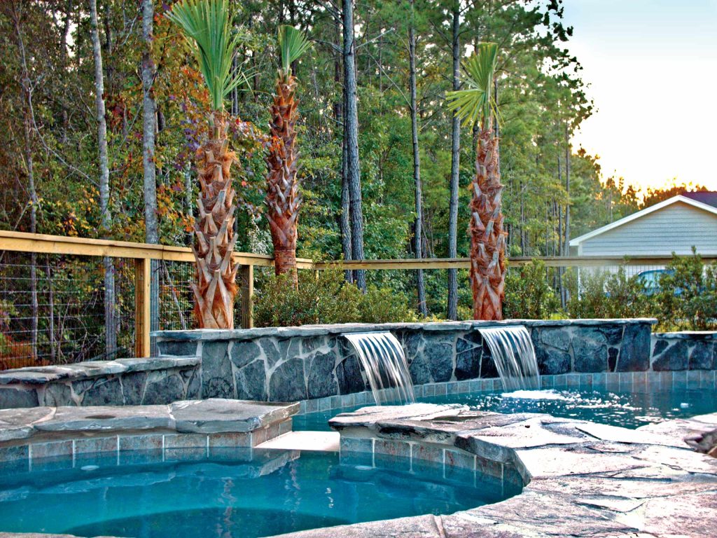 custom backyard swimming pool with stone water features and elevated spa area