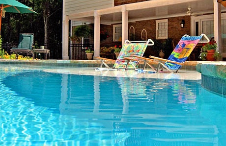 Poolside lounge chairs placed on a shallow tanning ledge in a luxury pool