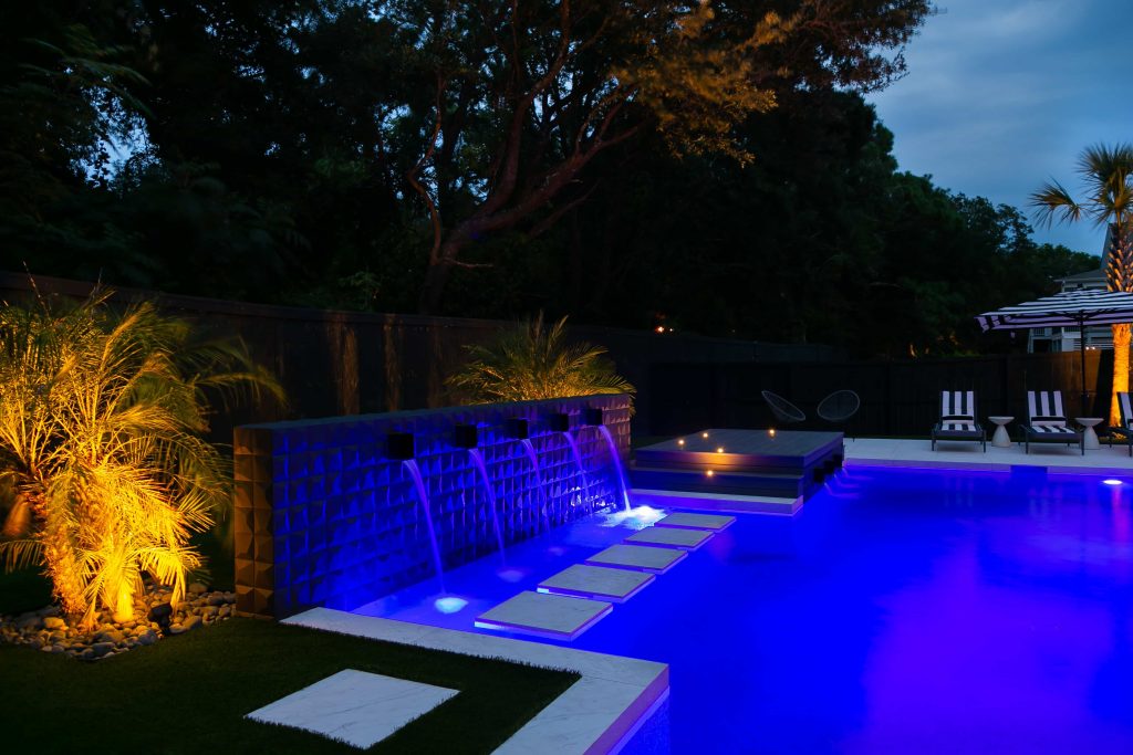 backyard swimming pool with color changing LED lighting at night
