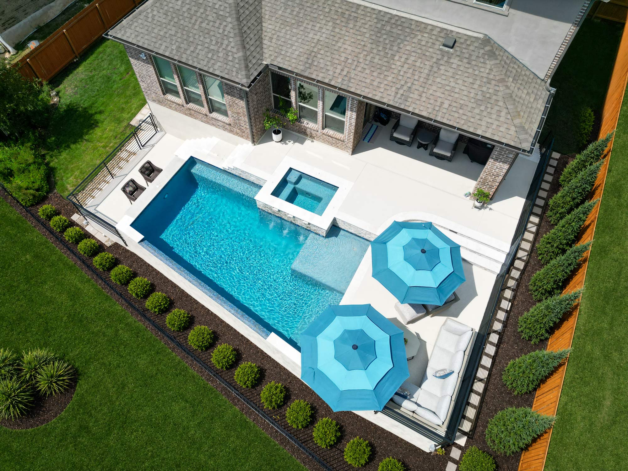 Geometric inground swimming pool with raised spa in San Antonio backyard