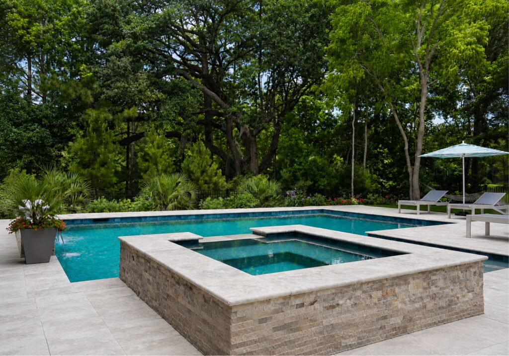 Custom gunite pool with raised spa and travertine patio, built to last for decades
