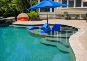Custom gunite pool with a tanning ledge, in-water loungers, and curved travertine patio