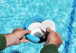 Adding a chlorine tablet to a floating pool dispenser to maintain proper sanitizer levels